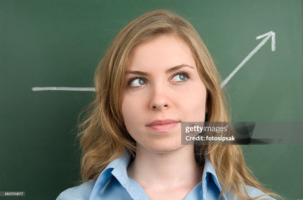 Woman looking away in front of chalkboard with arrow on it