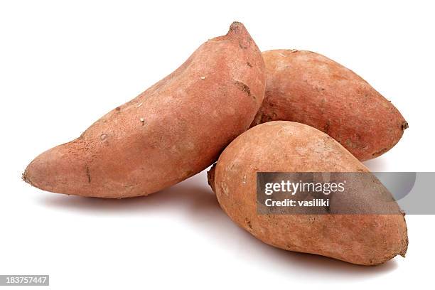 close-up of three raw sweet potatoes - zoete aardappel stockfoto's en -beelden
