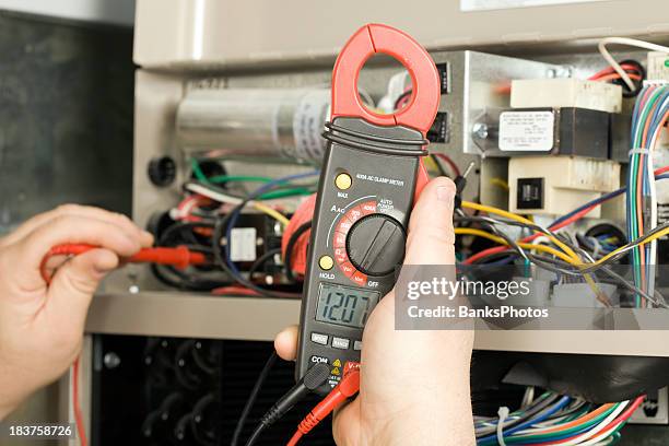 repairman checks voltage on geothermal hvac system - furnace stock pictures, royalty-free photos & images