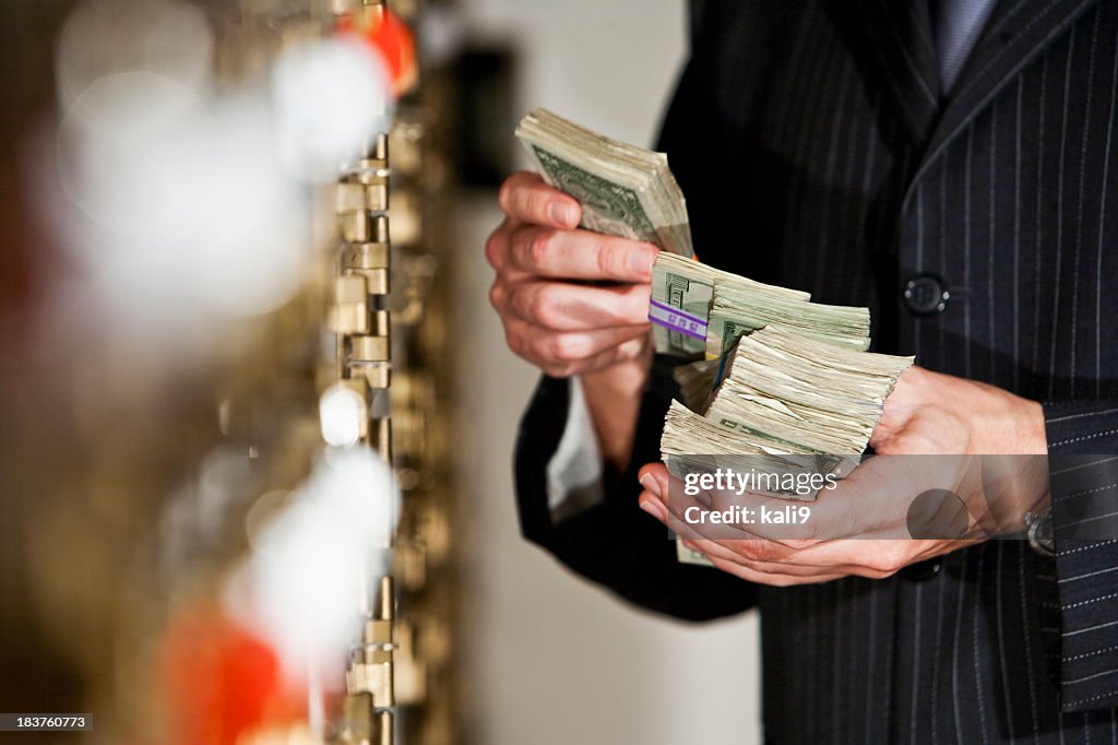 Man with cash by safety deposit boxes