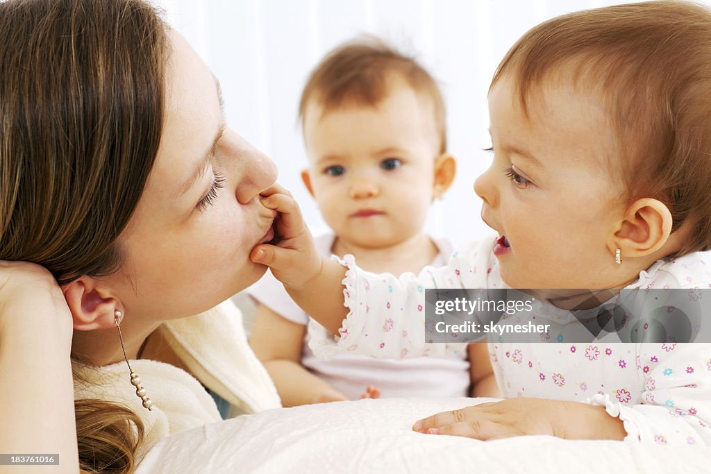 Mother playing with baby twin girl in bedroom.