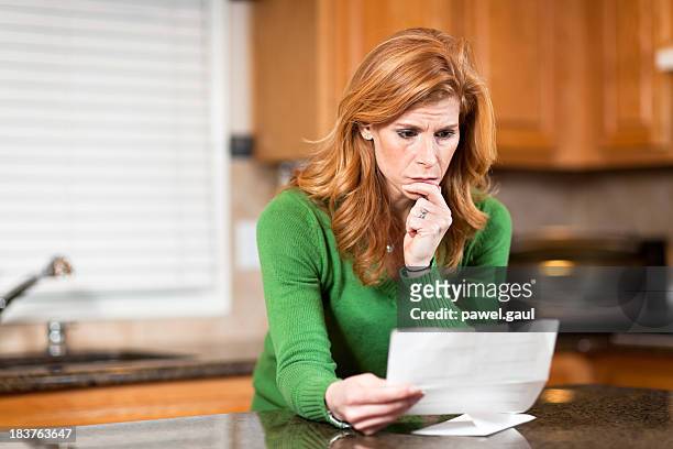worried woman reading bank statement - debit cards credit cards accepted stock pictures, royalty-free photos & images