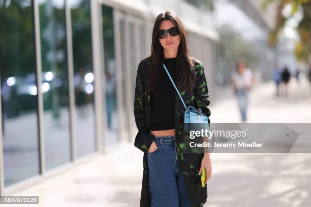 Sofia Yeganeh seen wearing black sunglasses, gold earrings, black cotton t-shirt, black / green batik pattern jacket, blue denim loose jeans / denim...