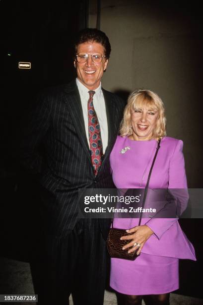 American actor Ted Danson, wearing a black pinstripe suit over a white shirt and a red-and-blue tie, and his wife, Casey Danson, who wears a lilac...