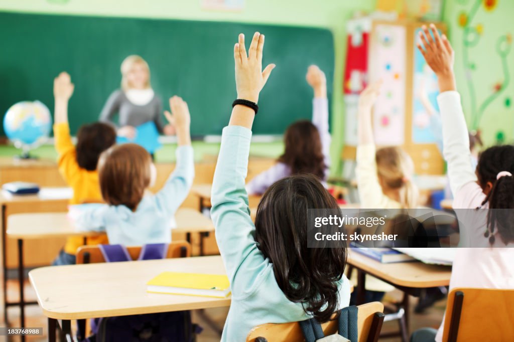 Children are raised hands in classroom.