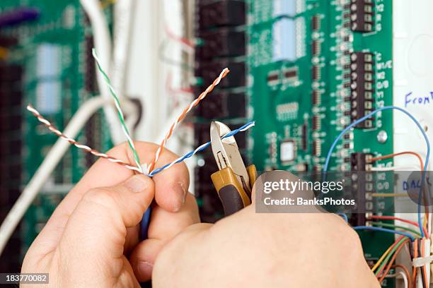 electrician cutting small paired wire with blurred pc board background - cable installation stock pictures, royalty-free photos & images