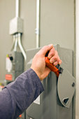 Worker Throwing Lever Switch on a Main Electrical Power Enclosure