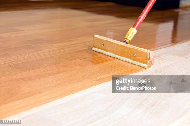 squeegee style brush applying clear polyurethane to hardwood floor - wood floor stockfoto's en -beelden