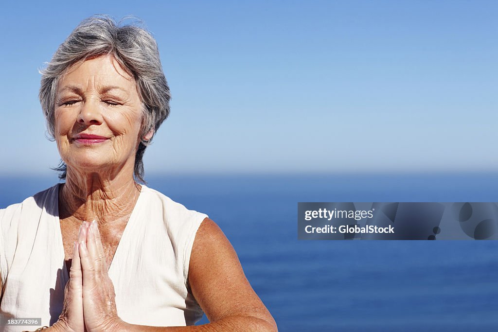 Woman practicing yoga with ocean in background