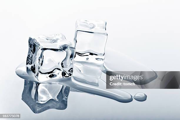 two ice cubes melting on reflected surface - melting stock pictures, royalty-free photos & images