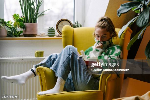 landscape format of a woman sitting relaxed in an armchair and reading - cosy woman stock pictures, royalty-free photos & images