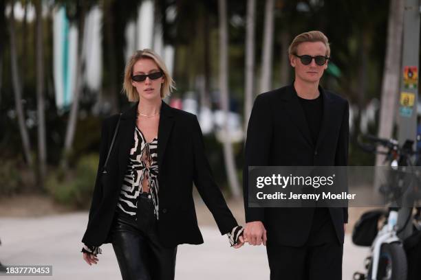 Ave Rohtla seen wearing black sunglasses, black / white transparent zebra pattern blouse, black blazer jacket, black leather straight leg pants,...