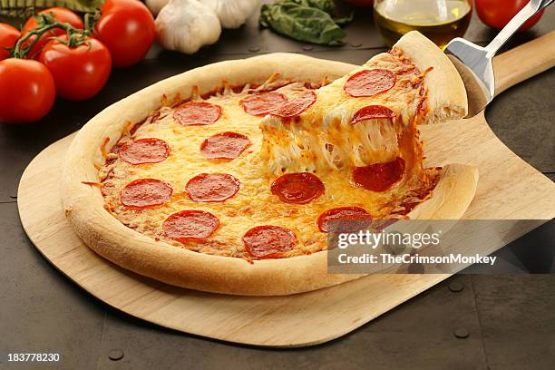 lifting a slice of warm pepperoni pizza - cheese pull stockfoto's en -beelden