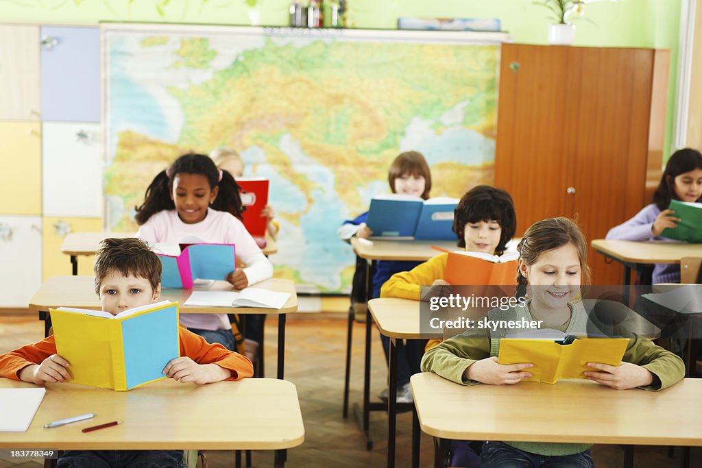 Children holding and reading textbooks in the classroom.