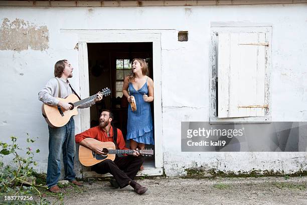 musicians playing in doorway of run-down building - countrymuziek stockfoto's en -beelden