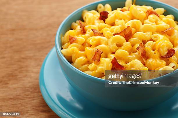 a blue bowl of macaroni and cheese with bacon pieces - macaroni and cheese stockfoto's en -beelden