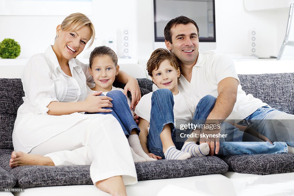 Happy family sitting on sofa and looking at the camera.