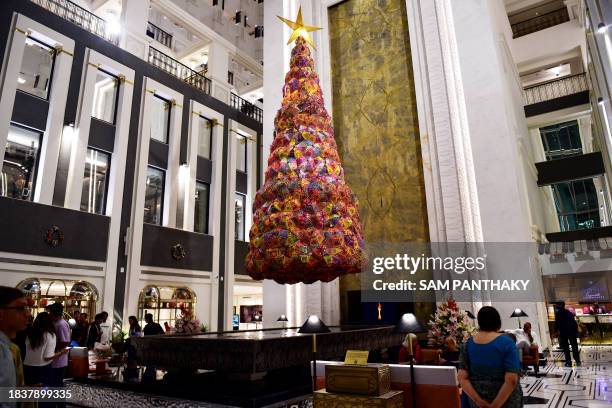 Guests walk past a Christmas tree made of about 300 umbrellas sourced from the Kutch region of India's Gujarat state, at the ITC Narmada hotel in...