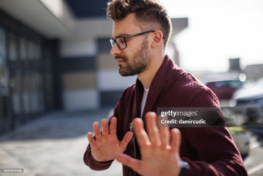 Young man showing stop gesture, saying no, protesting or refusing