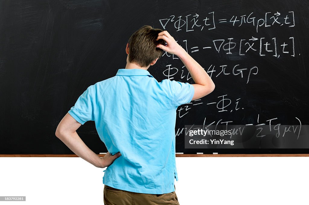 Teenager Student Scratching Head, Pondering Mathematics Formulas on Classroom Blackboard