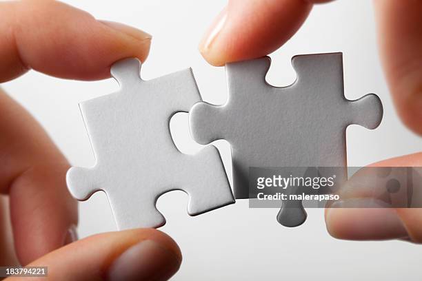connection. hands trying to fit two puzzle pieces together. - twee objecten stockfoto's en -beelden
