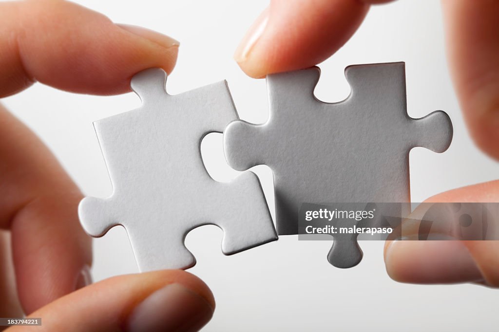 Connection. Hands trying to fit two puzzle pieces together.
