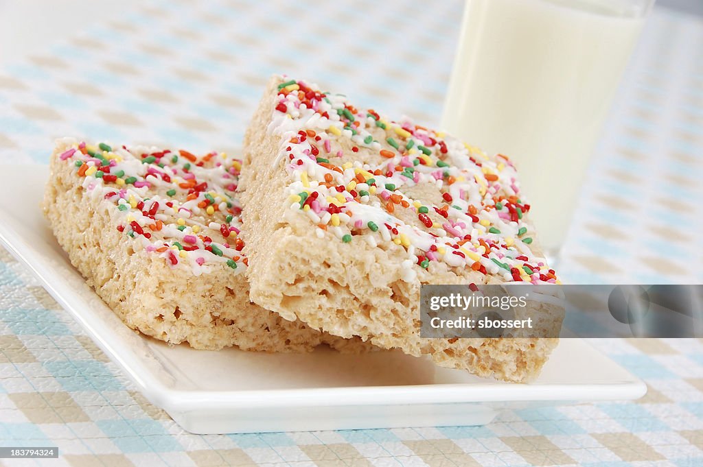 Rice crispy cereal bars with icing and sprinkles and milk