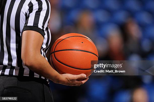 faceless female basketball referee holds ball in one hand - female umpire stockfoto's en -beelden