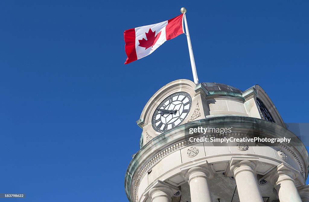Low angle view of a Canadian flag flying on a clock tower