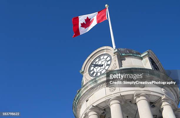 low angle view of a canadian flag flying on a clock tower - ontario canada stock pictures, royalty-free photos & images