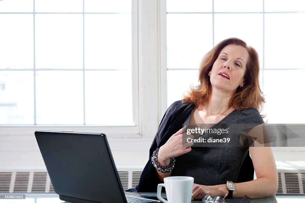 Menopausal woman having a hot flash at the office