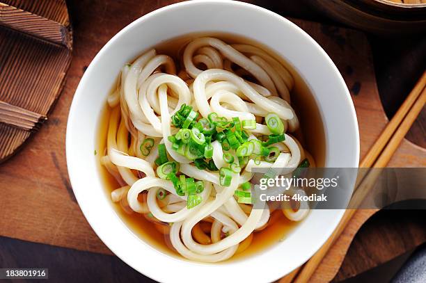 a bowl of udon noodles in the broth on a wooden board - udon noodles stock pictures, royalty-free photos & images