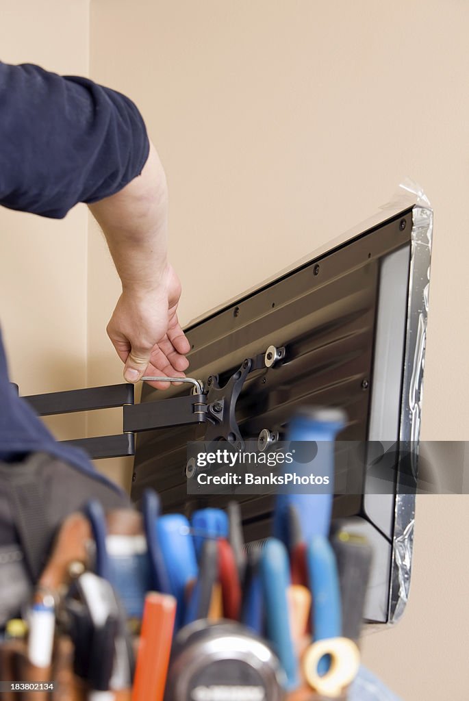 Worker Installing New TV with Tool Belt Foreground