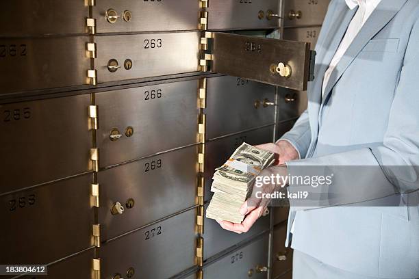 frau putting geld in den safe - safety deposit box stock-fotos und bilder