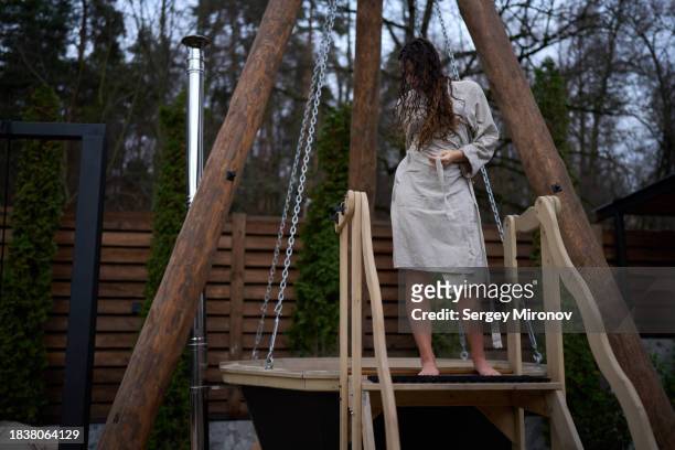 woman tying belt in robe after taking bath outdoors - woman bath tub wet hair stock pictures, royalty-free photos & images