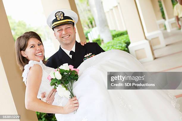 groom in navy uniform holding his new bride - military chic stock pictures, royalty-free photos & images