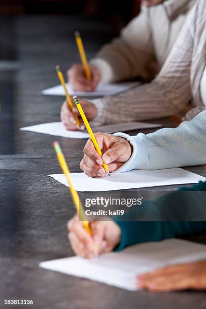 close up of people writing with pencils - examination table bildbanksfoton och bilder