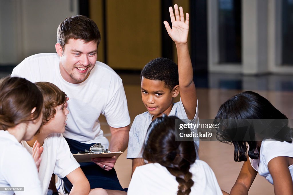 Diverse group of children in gym with coach