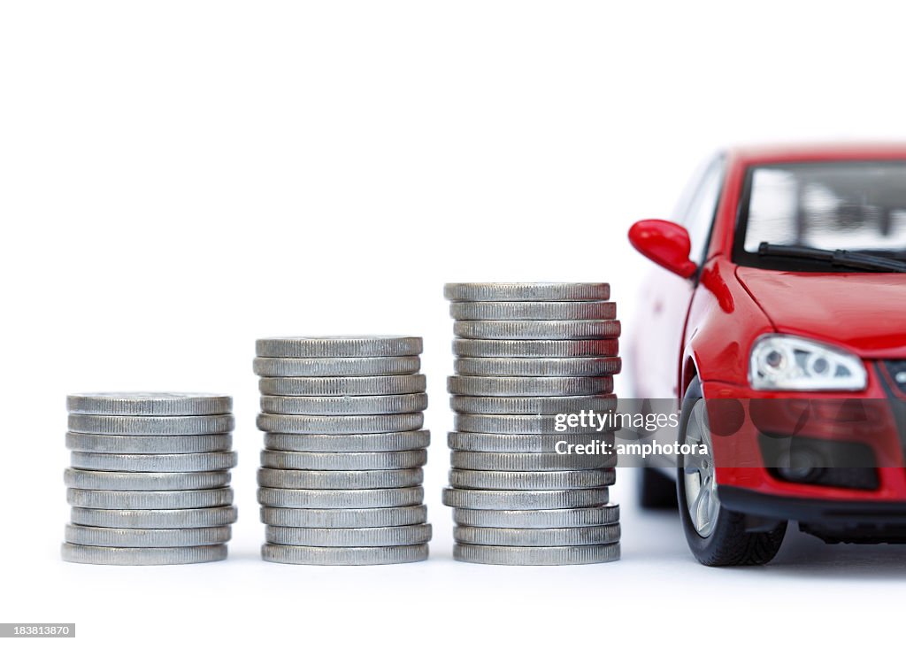 Stacks of giant silver coins next to a new red car