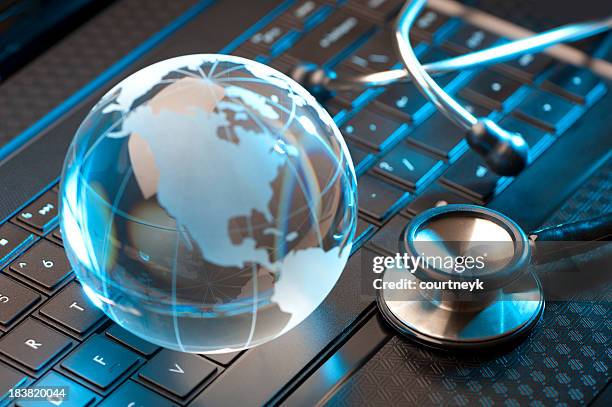 stethoscope and globe on a laptop - global healthcare stock pictures, royalty-free photos & images