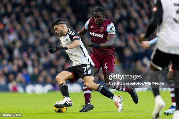 Raúl Jiménez of Fulham is challenged by Kurt Zouma of West Ham United during the Premier League match between Fulham FC and West Ham United at Craven...