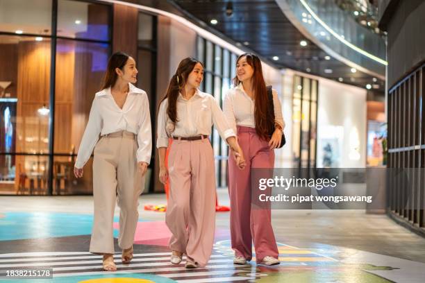 group of asian female friends are walking around a shopping mall. - a woman carrying a shopping bag walks out of a mall in beijing stock-fotos und bilder