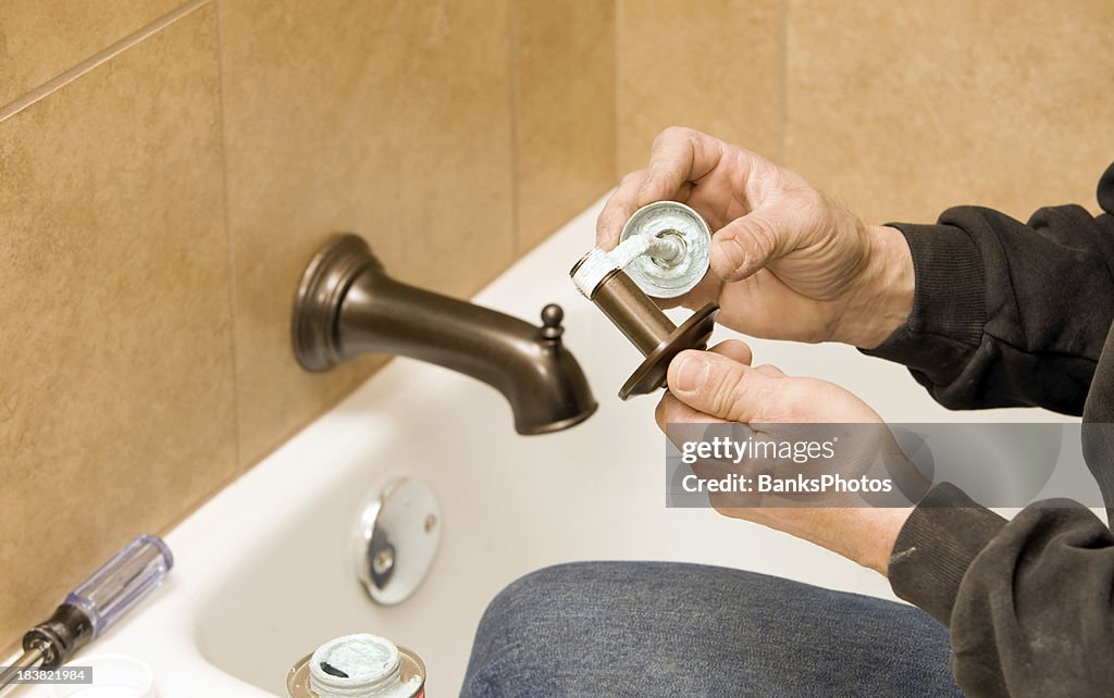 Plumber Applying Sealant around Shower Pipe