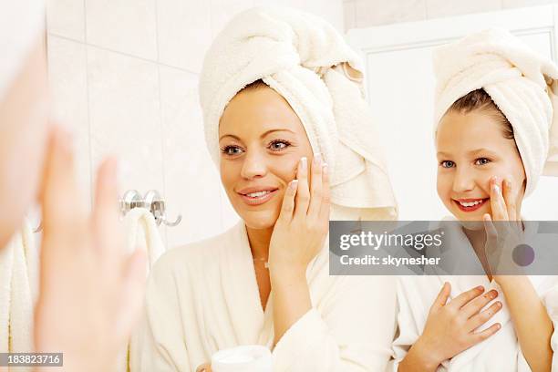 madre y su hija están poniendo en crema facial. - mother daughter towel fotografías e imágenes de stock