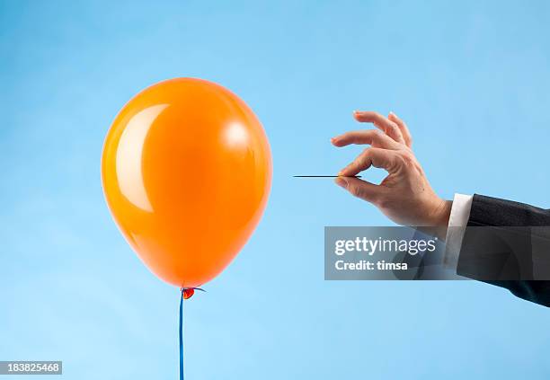 balloon attacked by hand with needle - balonnen stockfoto's en -beelden