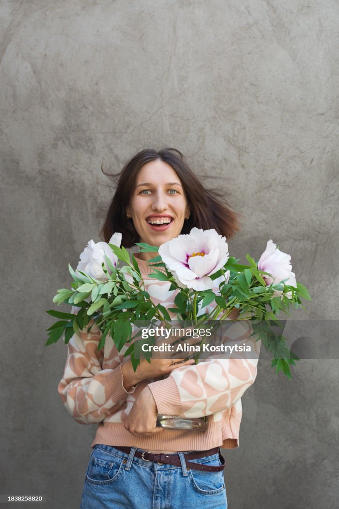 Cheerful woman with bouquet of white peonies