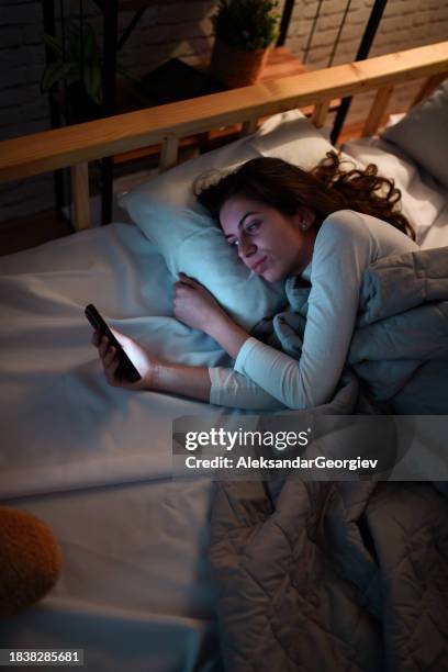 female with insomnia using smartphone at night - insomnia stock pictures, royalty-free photos & images