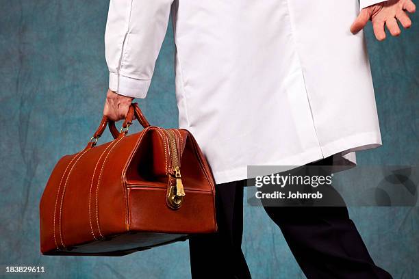 doctor in lab coat rushing, carrying his leather doctor bag - doctor's bag stock pictures, royalty-free photos & images