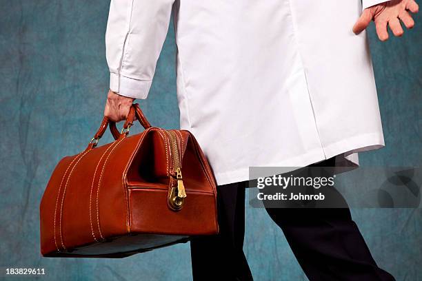 doctor in lab coat rushing, carrying his leather doctor bag - doctors bag stock pictures, royalty-free photos & images