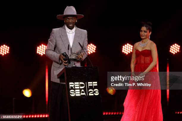 Baloji speaks on stage after receiving the Best Cinematic Contribution Award for 'OMEN' from jury member Freida Pinto during the Closing Ceremony at...